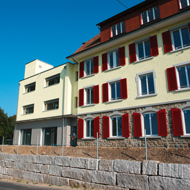 Gelbes Mehrfamilienhaus mit roten Fensterläden