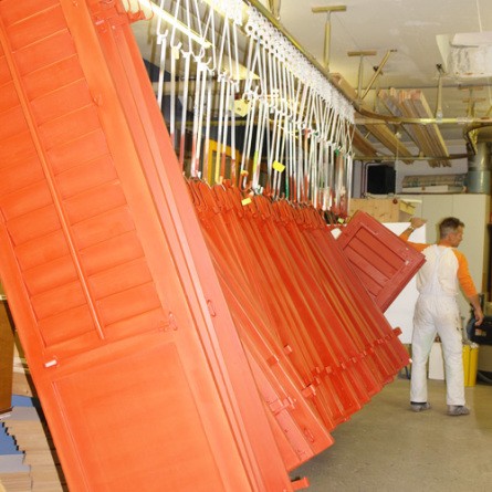 Frisch gespritzte rote Fensterläden hängen an der Hängebahn in der Werkstatt
